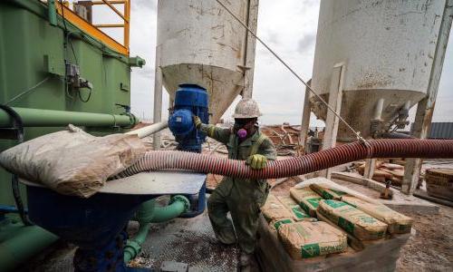 A man in an oxygen mask works on an oil rig. 